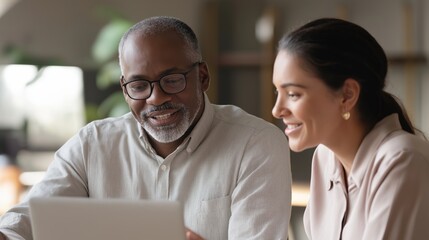 An African American woman collaborates with an adult male specialist on business tasks at a laptop, reflecting corporate analytics and workplace decision-making. Highlights digital strategy