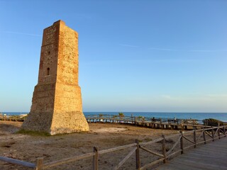 Torre Ladrones (Thieves Tower) at the coast of the Mediterranean Sea near Marbella in the light of the sunset and a blue sky, Cabopino, Costa del Sol, Andalusia, Spain