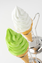 白背景に並ぶバニラと抹茶のソフトクリームコーンと金属スタンド