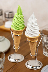 木製テーブルのカフェに並ぶ抹茶ソフトクリームとバニラソフトクリームコーン