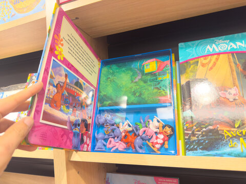 BELO HORIZONTE, MG, BRAZIL, DECEMBER 12, 2025 A child's hand opens a vibrant Disney Lilo & Stitch book, revealing character figures and a jungle scene for imaginative play.