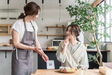 A cafe staff member and a female customer explaining and guiding a QR code