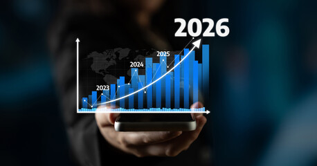 A person holds a smartphone displaying a financial graph illustrating significant growth from 2023 to 2026, capturing key projections in a digital age. Tessel