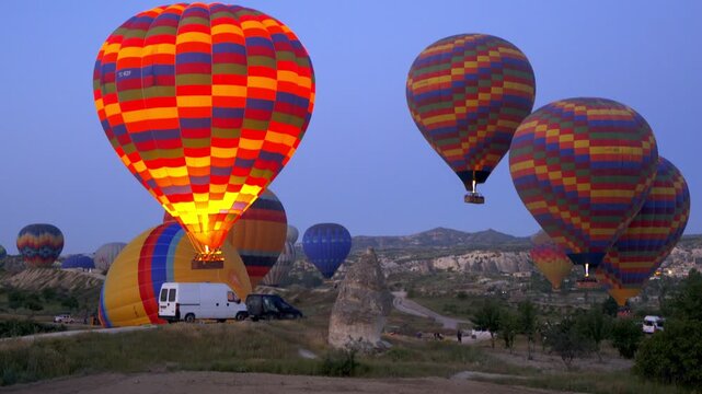 Colorful hot air balloons ascending at dawn with Uchisar town and unique rock formations in Cappadocia, Turkey