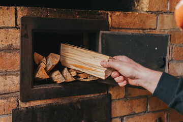  Loading Firewood Into a Stove.Heating with the stove. Heating a house with wood. Hand Placing Firewood in Brick Oven.Person Holding Stack of Firewood. 