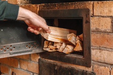  Heating a house with wood. Hand Placing Firewood in Brick Oven.Person Holding Stack of Firewood. 