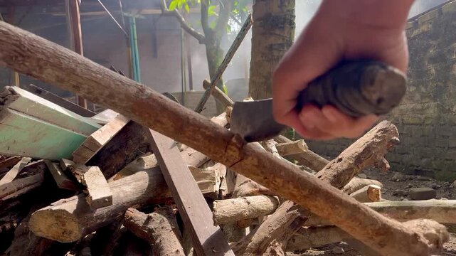 Someone chopping wood, smoking, behind the house, firewood and machete.