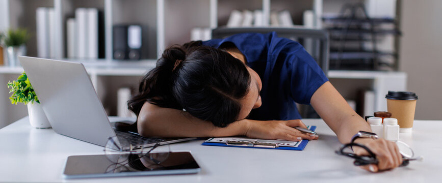 Doctor, Nurse, asian woman and headache with laptop at desk, clinic office or stress with thinking at job. Overworked medic, fatigue and burnout in hospital, book or anxiety for mental health by compu