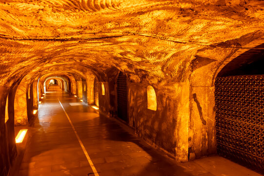Visit of deep and long underground caves with dusty bottles on racks, traditional method making champagne sparkling wine in Reims, Champagne, France
