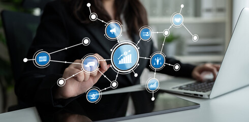 A businesswoman interacts with a digital data interface, showcasing statistical growth and analysis while working on a laptop in a professional environment. Crux