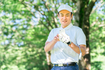 Male golfer using smartphone at golf course (app, score, score management, course strategy, course map)