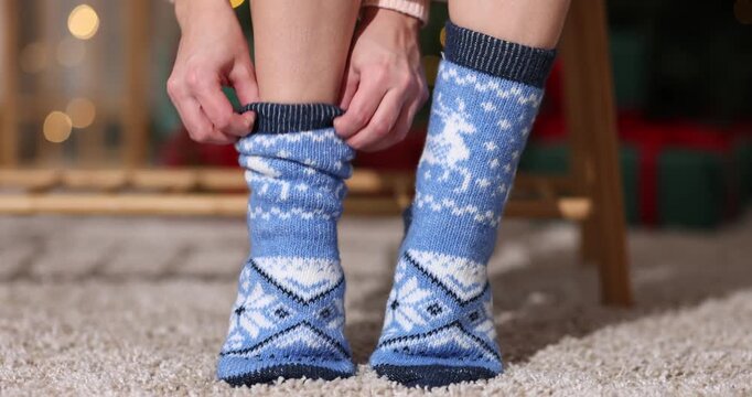 Woman putting on cozy blue socks at home, closeup