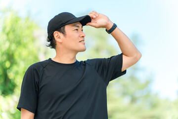 Asian man wearing sportswear in a park with fresh greenery