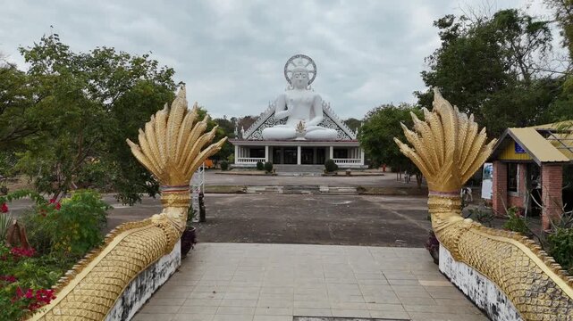 A long staircase leading to a stunning white Buddha statue at Pha Nang Khoi, Nakhon Phanom, Thailand. Peaceful spiritual landmark surrounded by nature and scenic views.