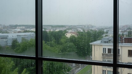 Rainy cityscape view from window with droplets on glass