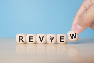 Review text on wooden cube blocks. Review evaluation time for review inspection assessment auditing. Business review for learning, improvement, planning and development for the future.