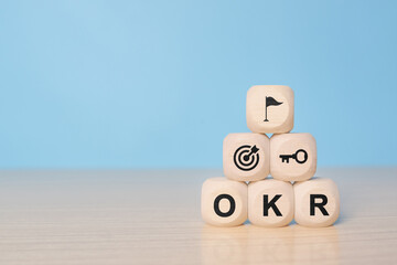 OKR Objectives, Key and Results wooden cube blocks on blue background. Business target and drive business and performance. Business and OKR - objectives and key results concept.