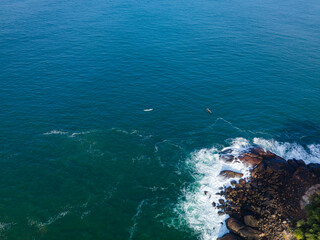 Aerial drone photo of ocean waves crashing against rocky shoreline. Dynamic naturel seascape with textured water,foam patterns and coastal rock viewed from above. minimalist and abstract.