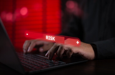 Businessman working on laptop with virtual risk level bar. Concept of risk management, financial analysis, investment security, crisis prevention, business uncertainty, and strategic decision.