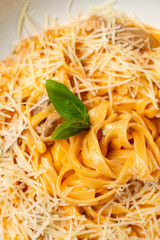 A tantalizing bowl of creamy pasta glistens under a generous layer of grated cheese. Fresh basil leaves rest on top, adding a vibrant touch. The scene evokes comfort and culinary joy