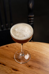 Enveloped in warm tones, a beautifully crafted cocktail sits poised on a polished wooden table, inviting patrons to enjoy an evening of relaxation in a charming bar atmosphere