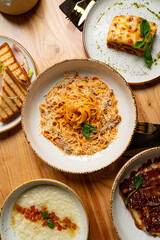 Mouthwatering dishes fill a rustic wooden table, showcasing vibrant pasta topped with cheese, rich lasagna, and creamy polenta. Perfect for a delightful dining experience