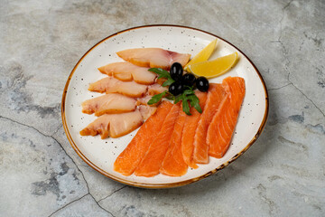 A vibrant platter showcases thinly sliced fresh salmon and white fish, garnished with black olives and bright lemon wedges. Perfect for a refreshing meal or appetizer