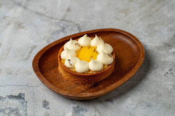 A sweet pastry features a bright yellow filling, adorned with fluffy white peaks and touches of shimmering gold. Perfect for an elegant dessert moment
