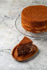A delicious layered cake with a toasty crumb topping sits on a glass stand. A slice rests on a wooden plate, inviting everyone to enjoy this sweet treat. The scene feels warm and inviting