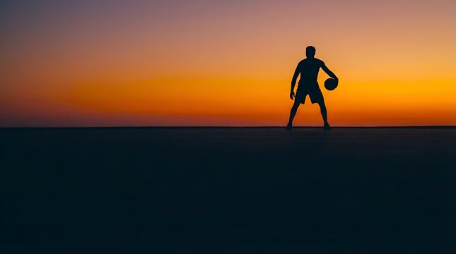 Silhouette of a basketball player holding a ball against a vibrant orange and yellow sunset sky, with a dark foreground.