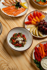 A vibrant array of fresh fruits and vegetables is beautifully arranged on rustic wooden tables. Plates hold smoked salmon, colorful sliced fruit, and a medley of dips, inviting sharing and enjoyment