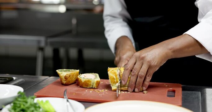 Hands, chef and cutting beef wellington in restaurant kitchen, catering service and meal order. Person, cooking and cuisine for food on board with culinary skills, gourmet dish and pastry at diner - Powered by Adobe