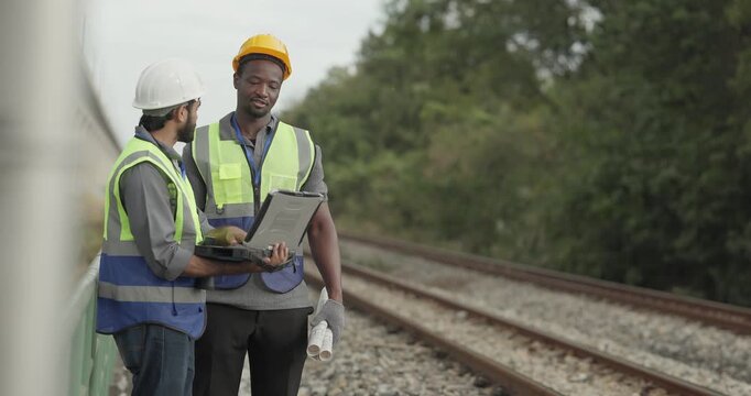 A rail engineer and field technician inspect the railway corridor while discussing zero emission solutions and green infrastructure strategies to reduce the network carbon footprint.
