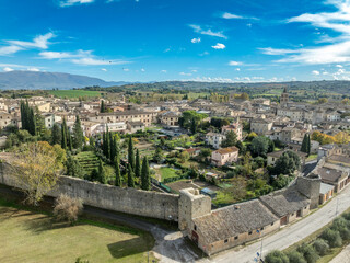 Aerial view of Bevagna medieval town center with city walls, gates, towers, Gothic churches with blue sky