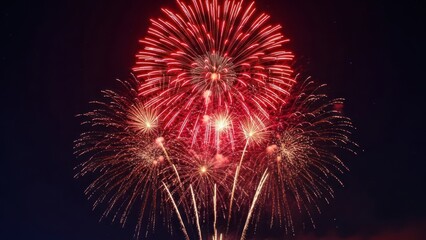 A burst of vibrant red fireworks exploding against a dark, star-speckled sky