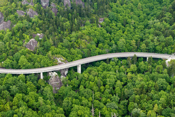 Winding mountain road in summer woods. Linn Cove Viaduct in Appalachian mountains in North Carolina with fresh green forest trees in summertime season. Beauty of USA nature