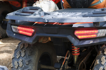Rear view of rugged atv vehicle showing bright red taillight and offroad tire tread ready for extreme adventure and exciting outdoor recreation activity on dirt track