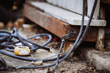 Close-up of an unsafe welding setup with a makeshift ground connection on a rusty steel beam. Concept of industrial workplace hazards, poor electrical contact, and construction safety negligence.