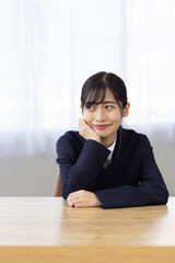 Young Businesswoman Smiling with Hands Under Chin at Desk