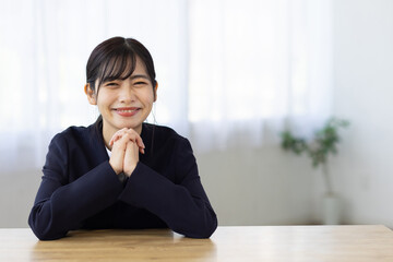 Young Businesswoman Smiling with Hands Under Chin at Desk