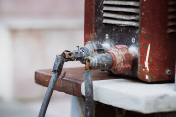 Close-up of damaged electrical cable connectors on an old welding machine. Concept of industrial equipment failure, fire hazard, and the importance of regular maintenance in the workplace.