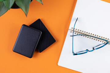 Leather wallets and glasses on orange background