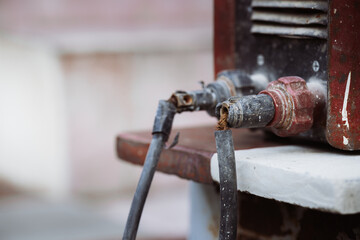Extreme close-up of a frayed and damaged electrical terminal on a vintage welding machine. Illustrating industrial safety violations, fire risk, and hazardous work conditions due to poor maintenance.