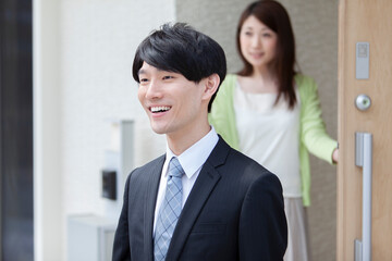 玄関先で夫を見送る妻 © UTS