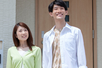 自宅の玄関先に立つ夫婦 © UTS