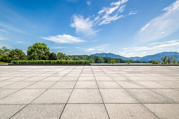 Empty square floor with a scenic lake and green mountains under a blue sky.
