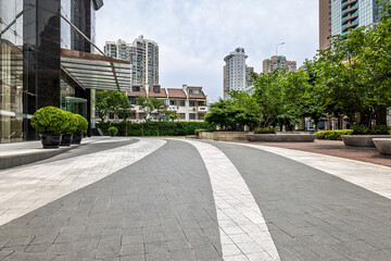 Empty curved paved pathway in a modern city with buildings and trees.