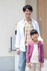 玄関先に立つ父親と娘