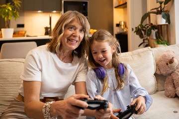 Granddaughter and grandmother laughing while enjoying a video game on the couch