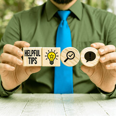 Business person holding wooden blocks with icons sees the inscription HELPFUL TIPS. Helpful Tips Business Concept. Top tip and quick advice.new